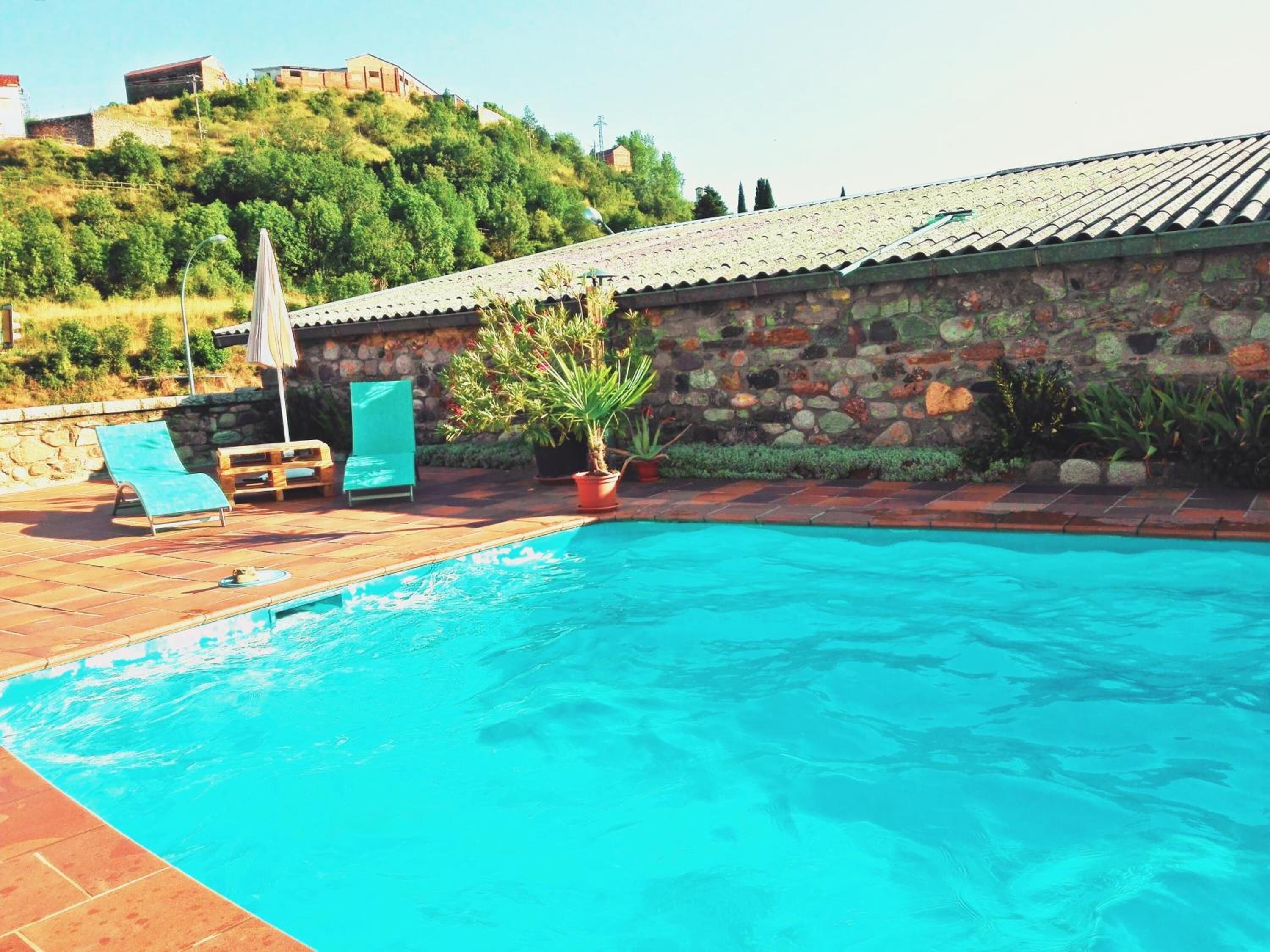 A swimming pool with lounge chairs and a stone wall.