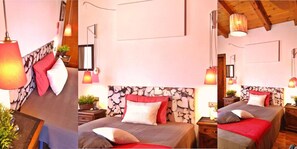 Un dormitorio acogedor con cabecera de piedra, dos mesitas de noche con lámparas y una cama con ropa de cama roja y blanca.