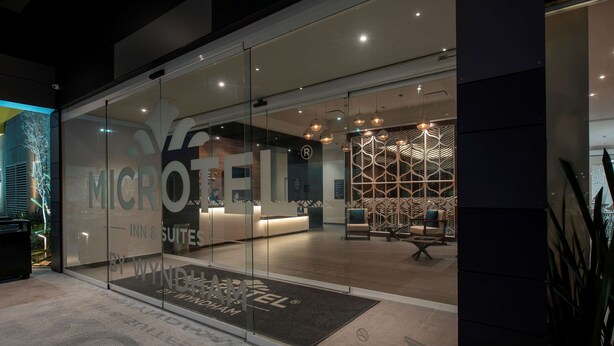 Un interior de hotel moderno con una recepción, un diseño de pared con motivos y una zona de estar.