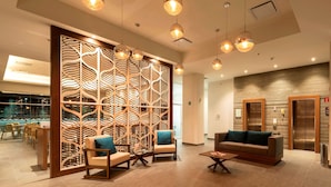 Un moderno vestíbulo con un muro decorativo de madera, zona de estar y mostrador de recepción.
