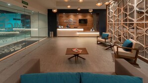 Un moderno vestíbulo de hotel con mostrador de recepción, zona de estar y una pared decorativa.