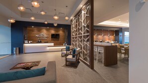 Un moderno vestíbulo de hotel con una recepción, zona de estar y un bar.