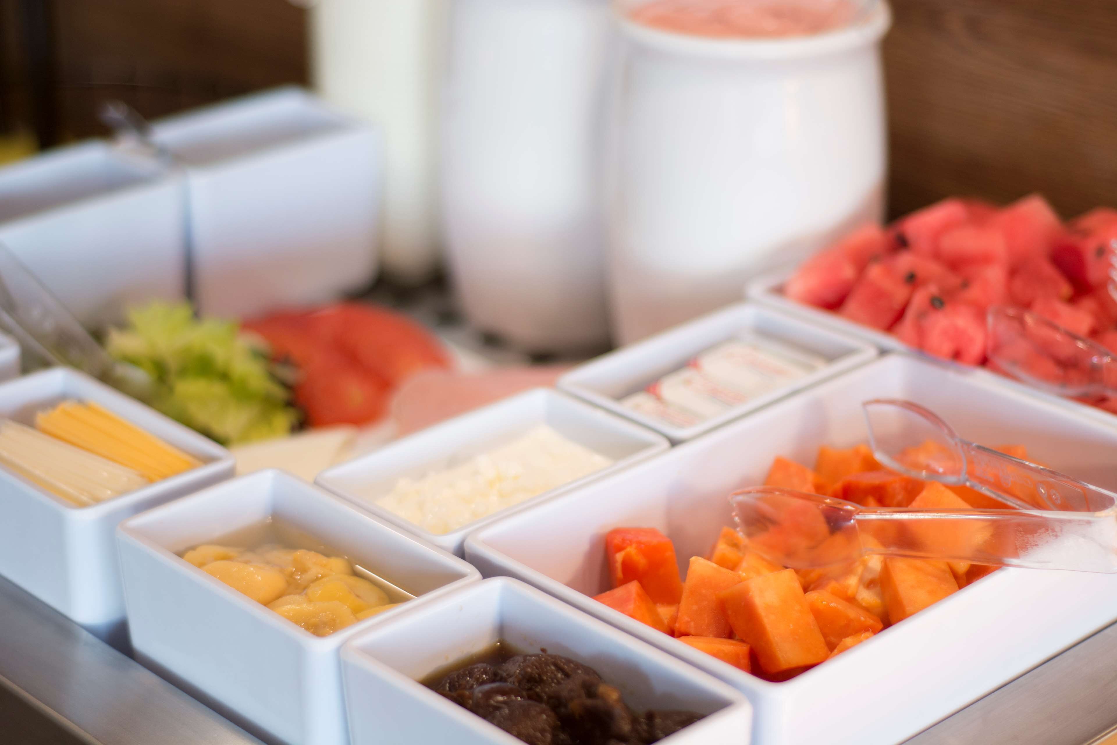 A buffet with various food items including fruits, vegetables, and condiments.