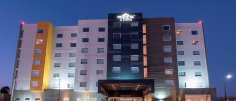 A multi-story hotel with a modern facade, illuminated signage, and a well-lit entrance.
