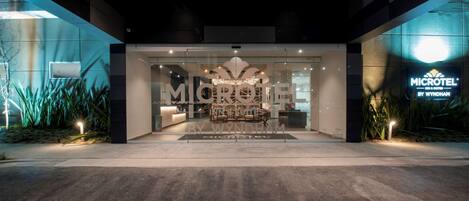 A modern hotel entrance with a reception desk, glass doors, and a sign for 'MICROTEL BY WYNDHAM'.