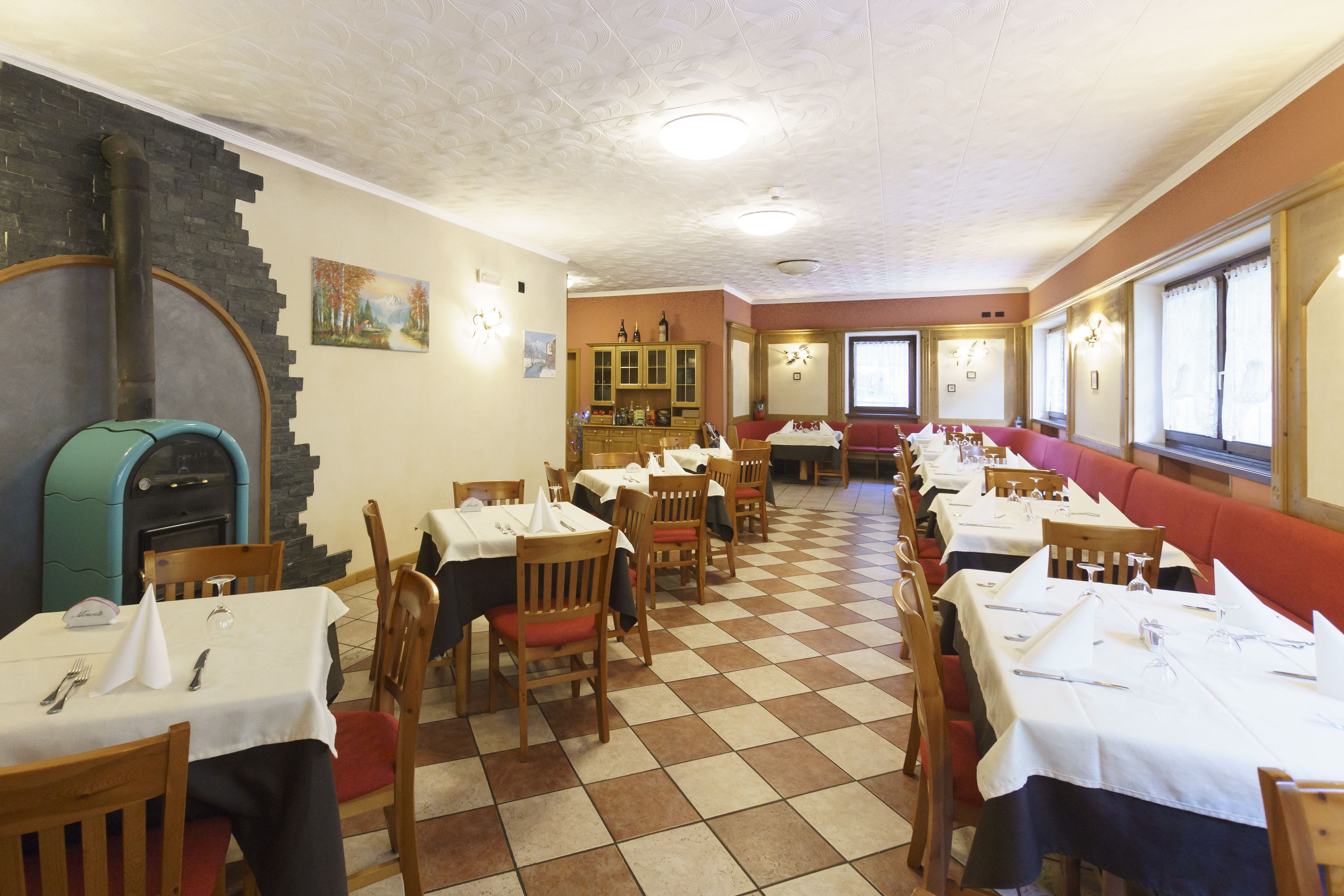 Een restaurant met geruit vloerkleed, houten stoelen en tafels met witte tafellinnen.