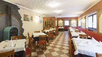 Un restaurant amb sostre de taules de joc, cadires de fusta i taules cobertes amb teles blanques.