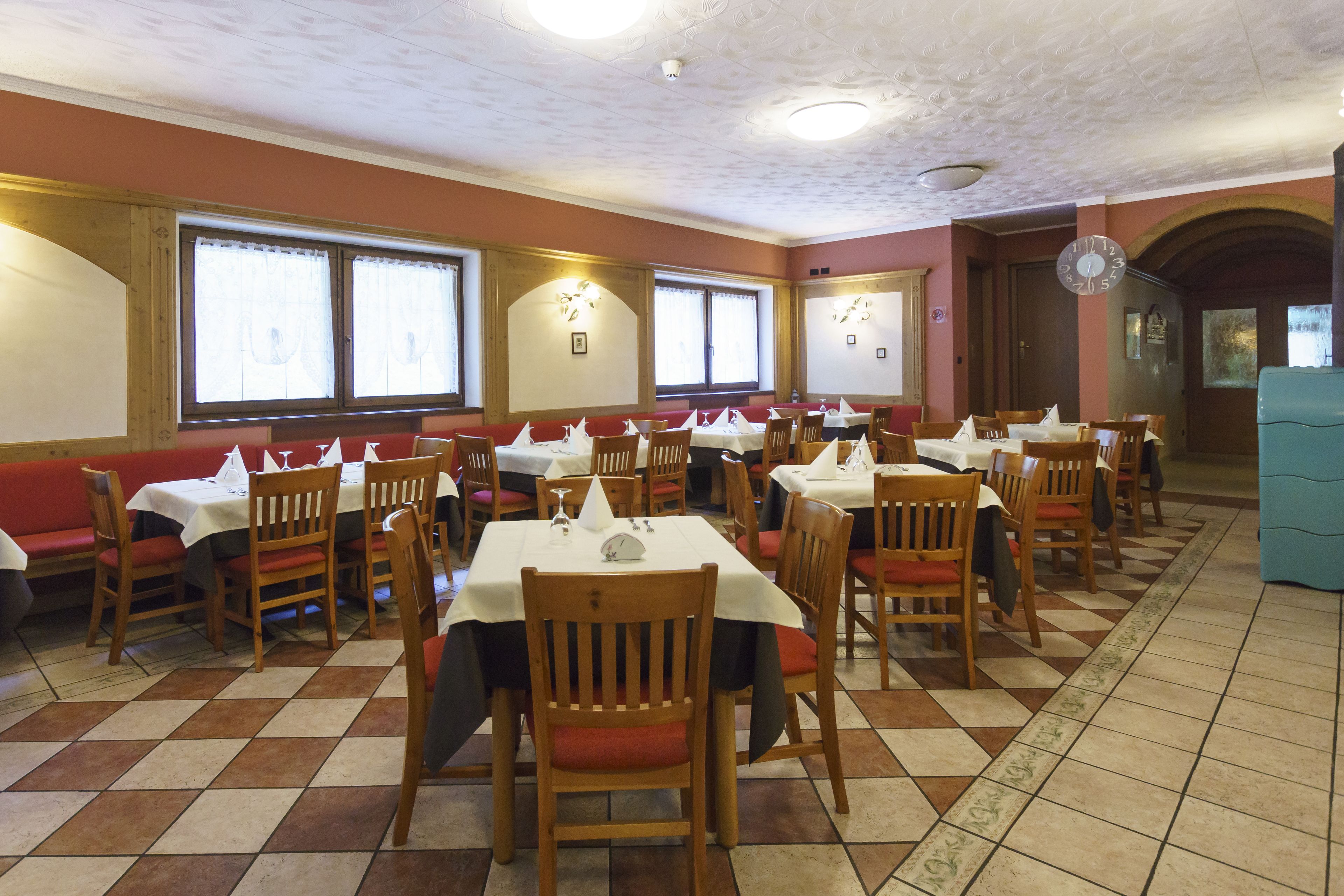Un restaurant doté de nombreuses tables et de banquettes, de chaises en bois et d’un sol carrelé.