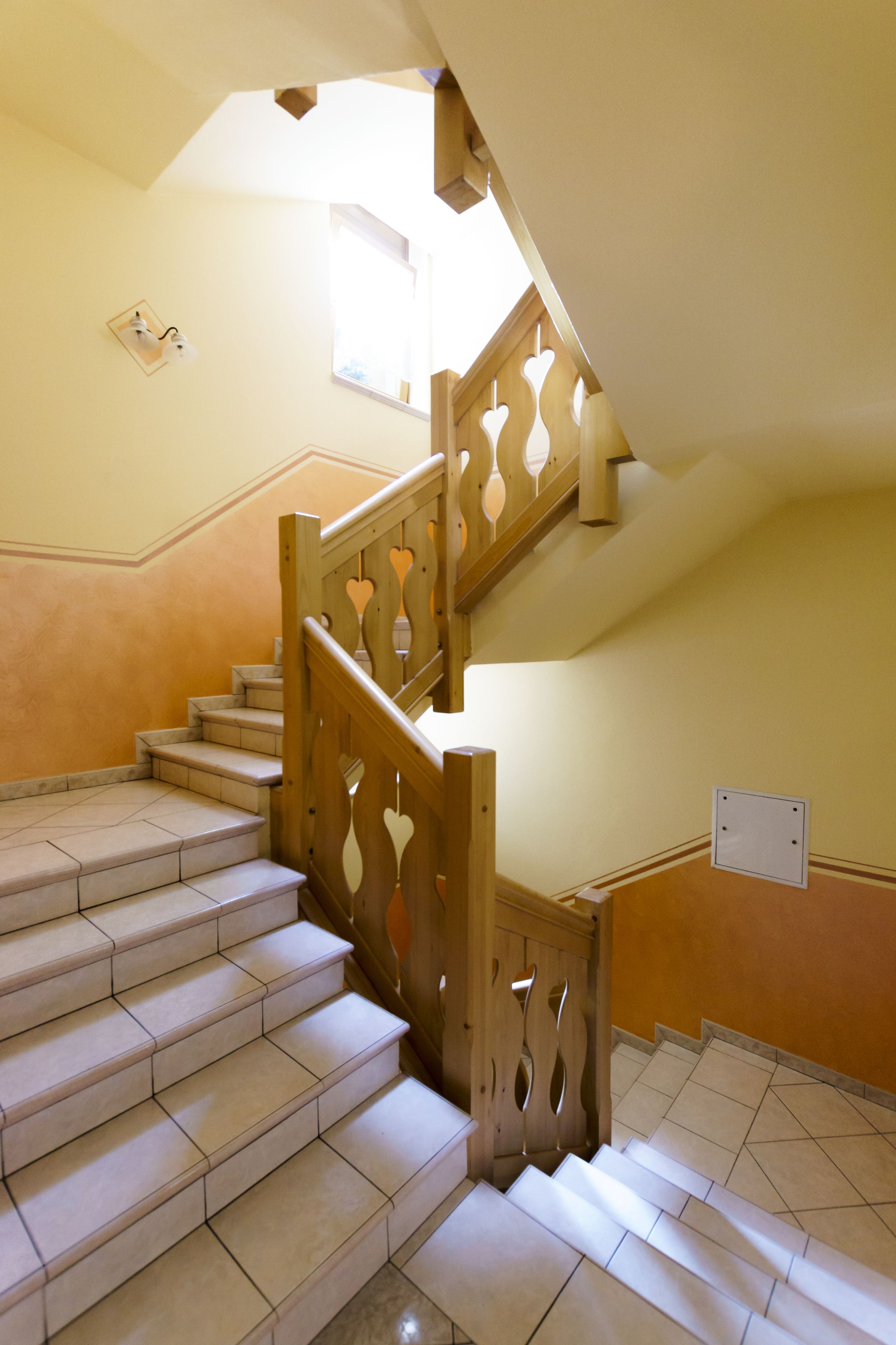 Eine Treppe mit Holzgeländern und beigefarbenen Fliesen.
