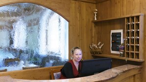 Ein Empfangstresen mit großem Fenster, Holzvertäfelung und einer kleinen Ablagefläche mit Dekoration.
