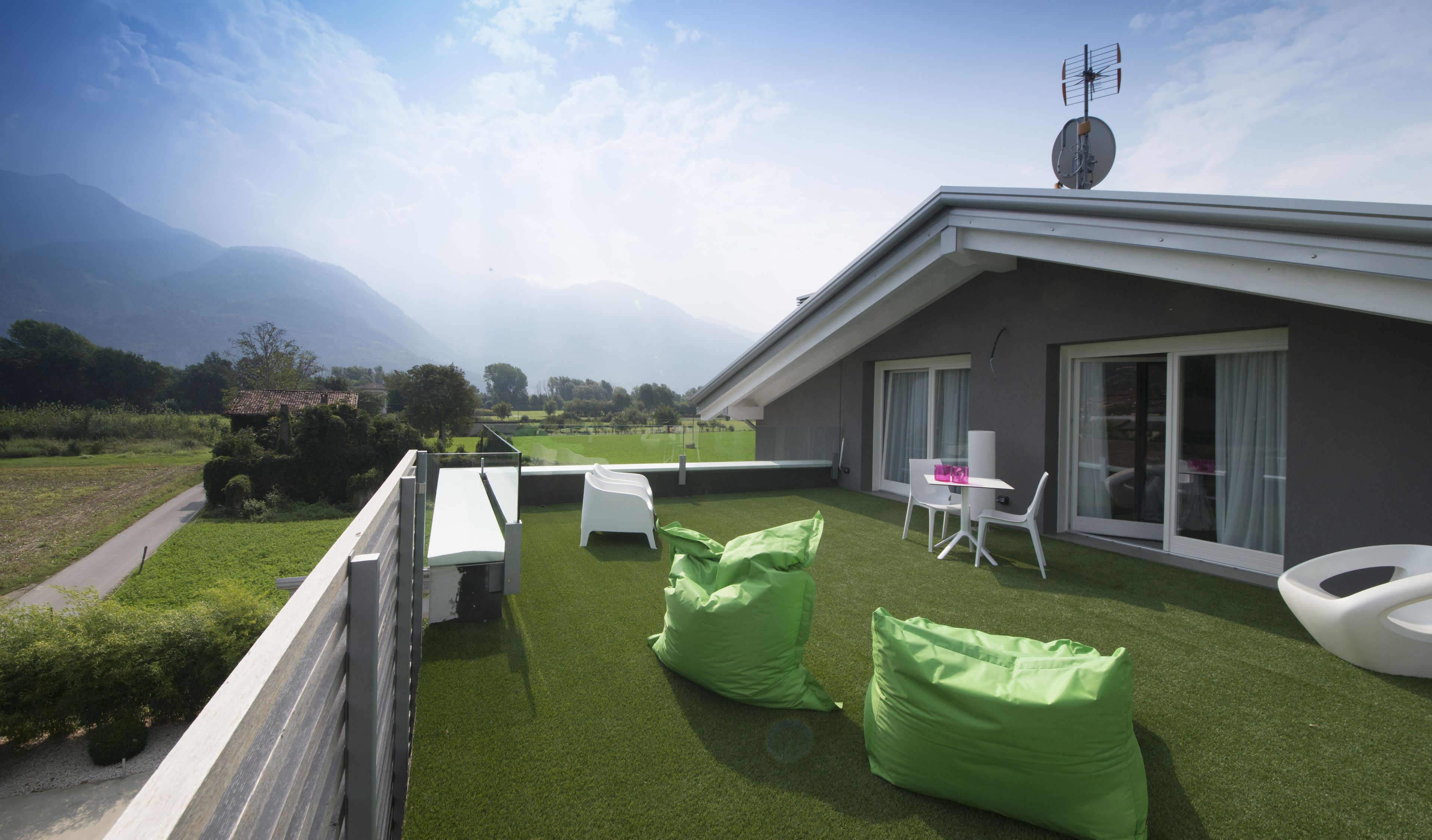 Eine Dachterrasse mit Blick auf Berge, einer Satellitenschüssel und einem Tisch mit Stühlen.