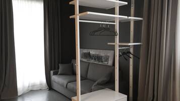 Une pièce moderne avec un canapé gris, un meuble de rangement blanc suspendu et un tableau au mur.