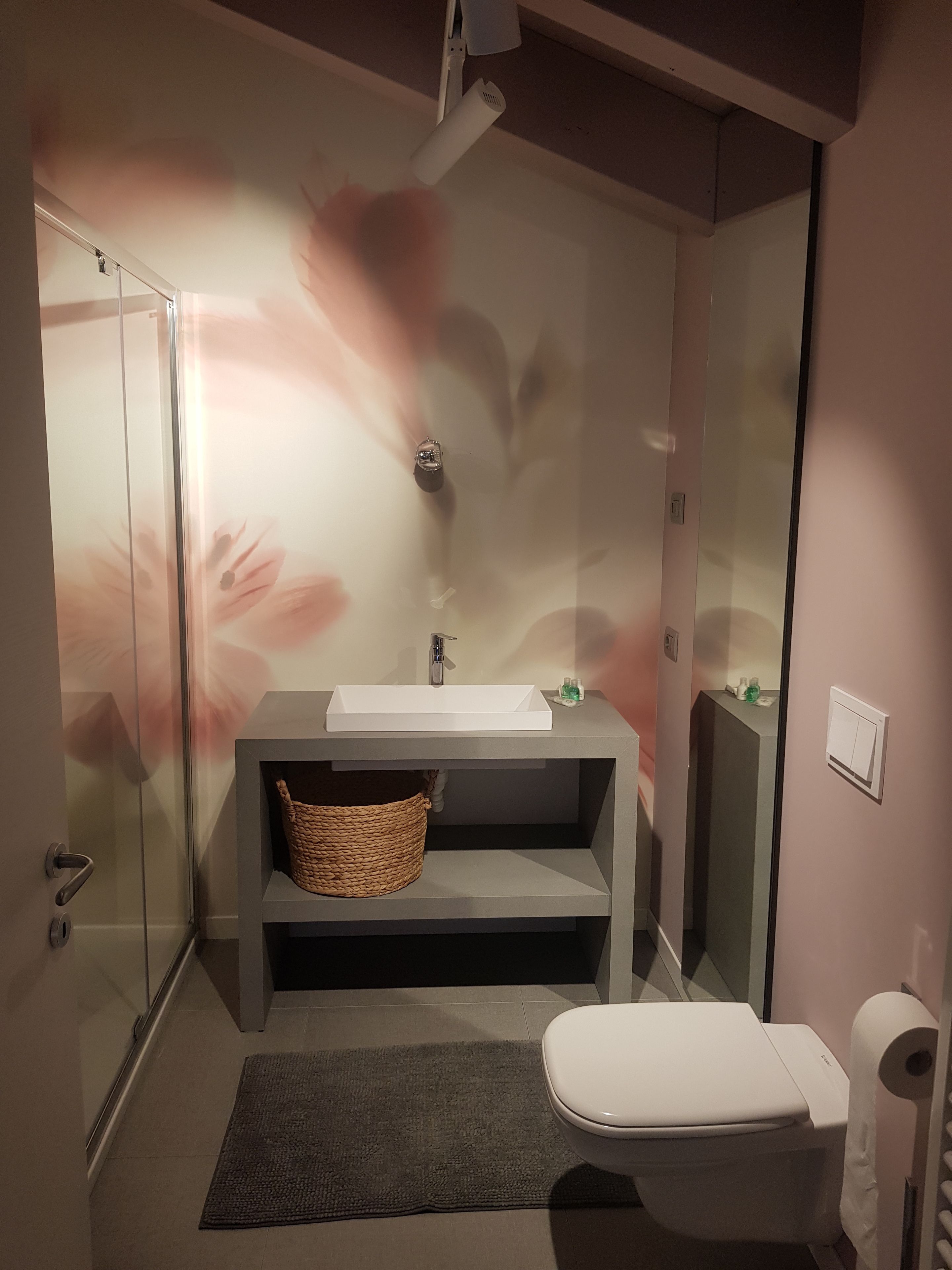 A modern bathroom with a glass shower enclosure, a white sink, and a toilet.