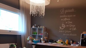 A modern dining area with white furniture, a chandelier, and a wall with a motivational quote. - Art B&B Design (Costa Volpino)