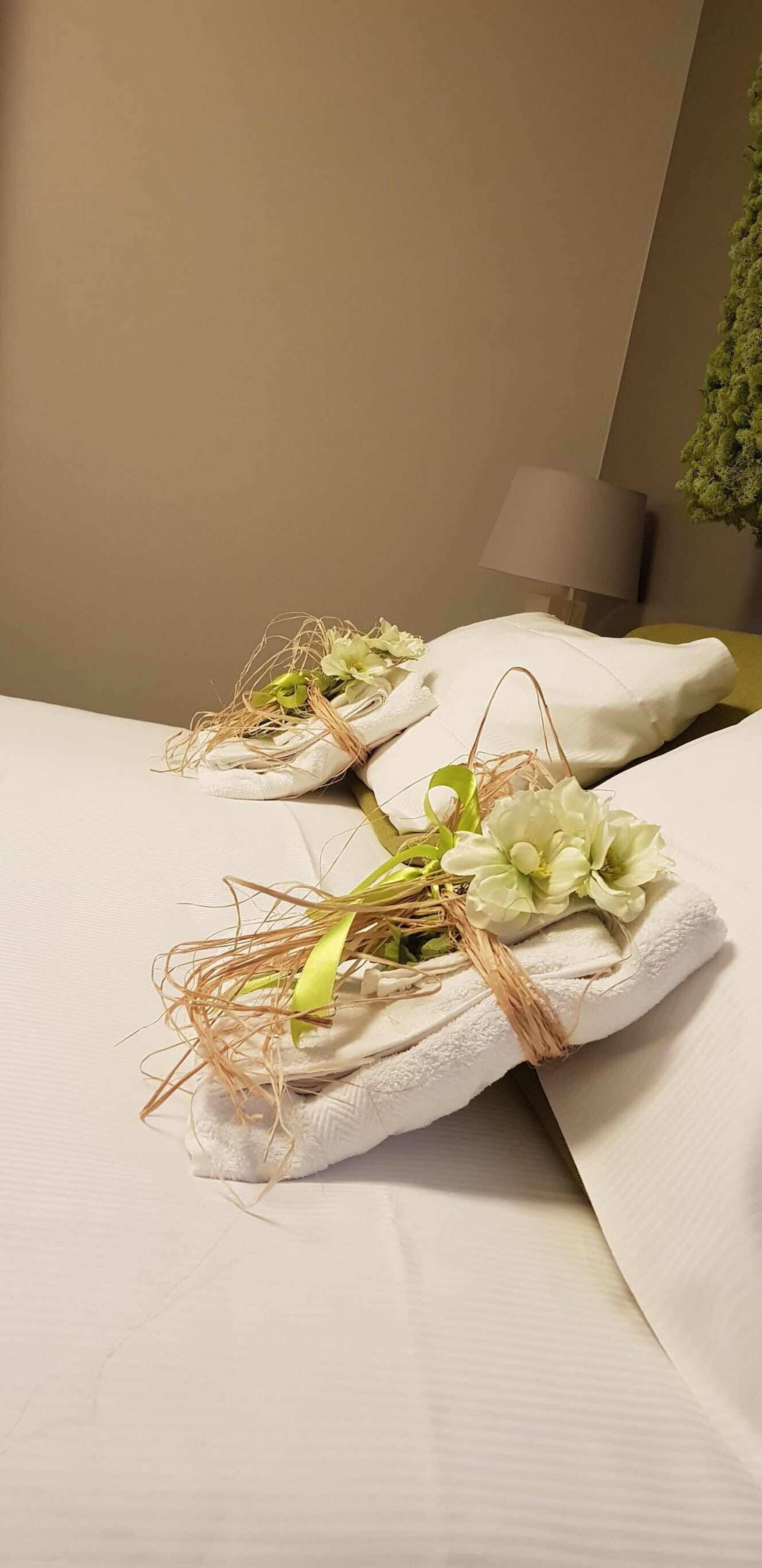 A neatly made bed with white linens and decorative floral arrangements.