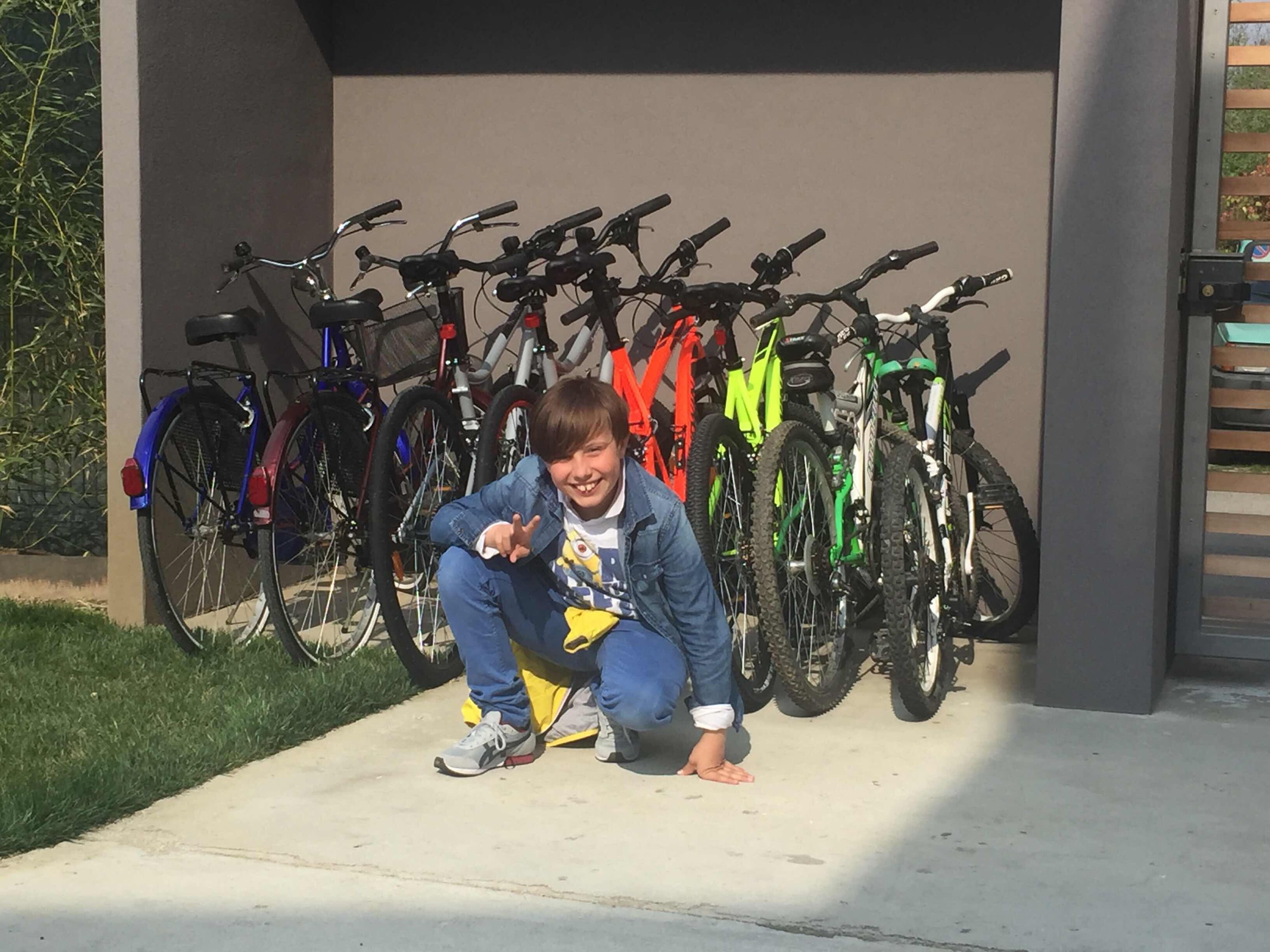 A person crouching in front of a row of bicycles.