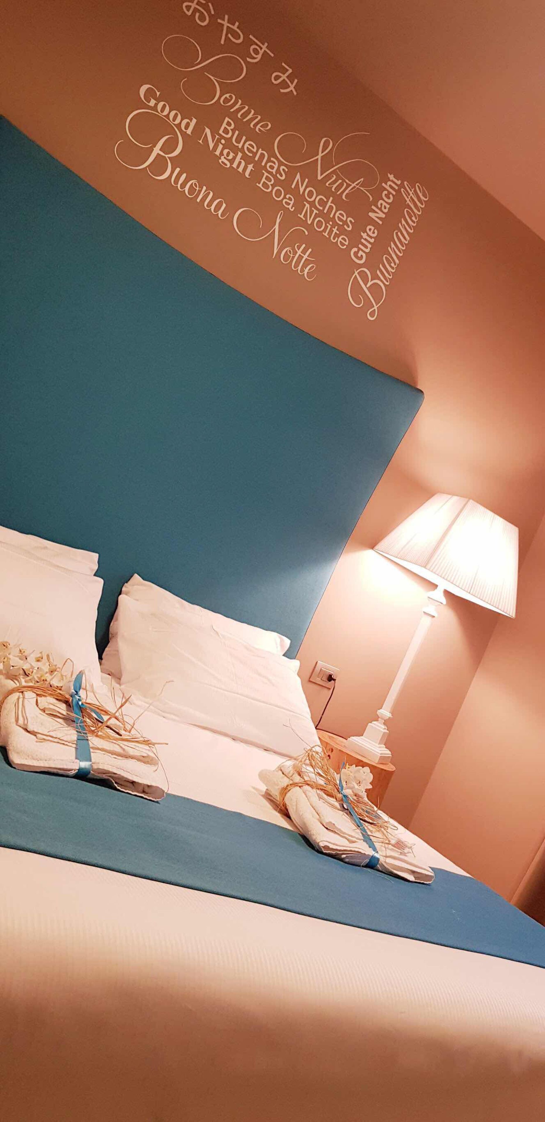 Ein Hotelzimmer mit einem Bett, Kissen und einer Wand mit einer italienischen Schrift.