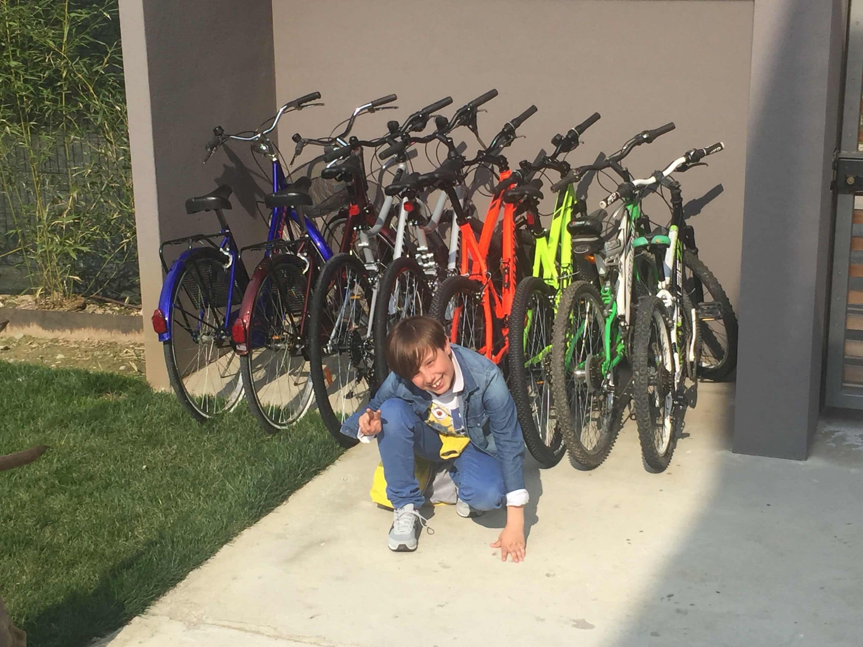 Un enfant accroupi devant une rangée de vélos.