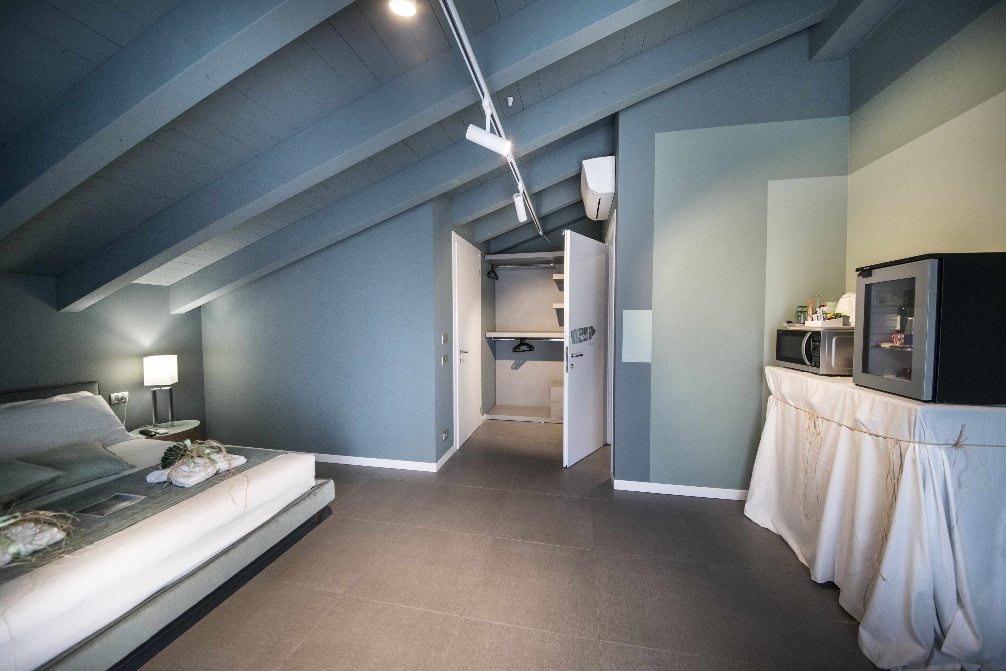A modern bedroom with a bed, bedside table, and a nightstand. There is a doorway leading to a bathroom.