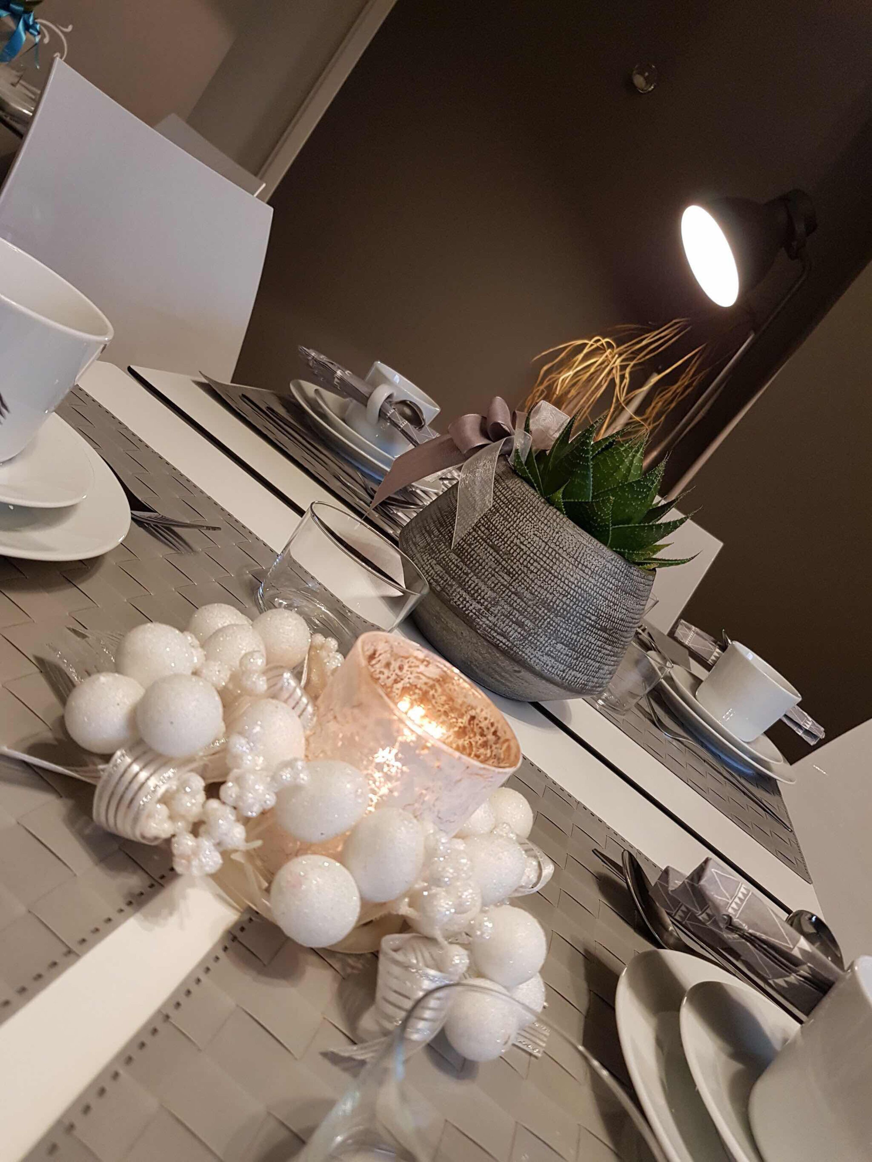 A dining table set with plates, cutlery, and decorative items like a candle and a plant.