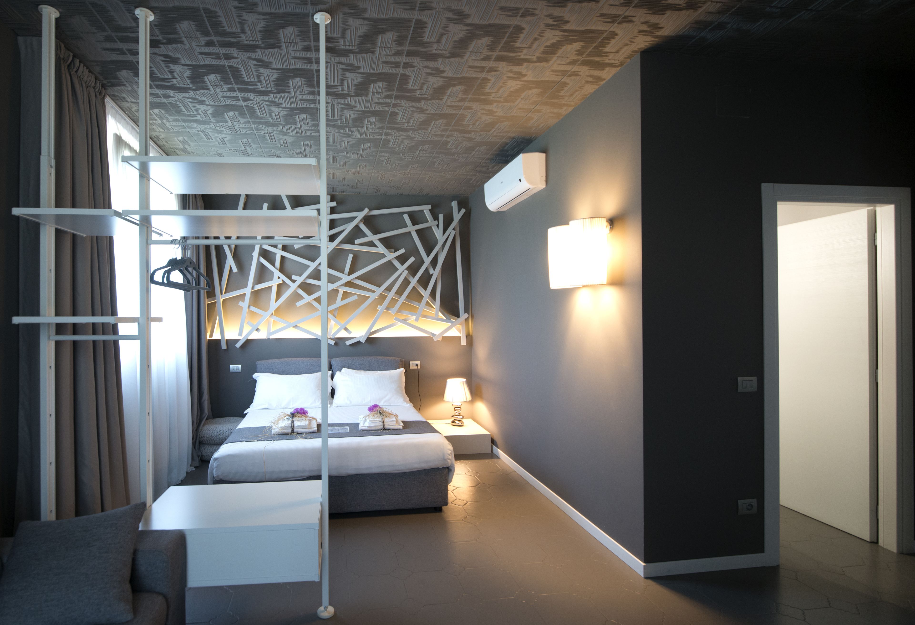 Une chambre d’hôtel moderne, dotée d’un lit, d’une table de chevet et d’un design de plafond original.