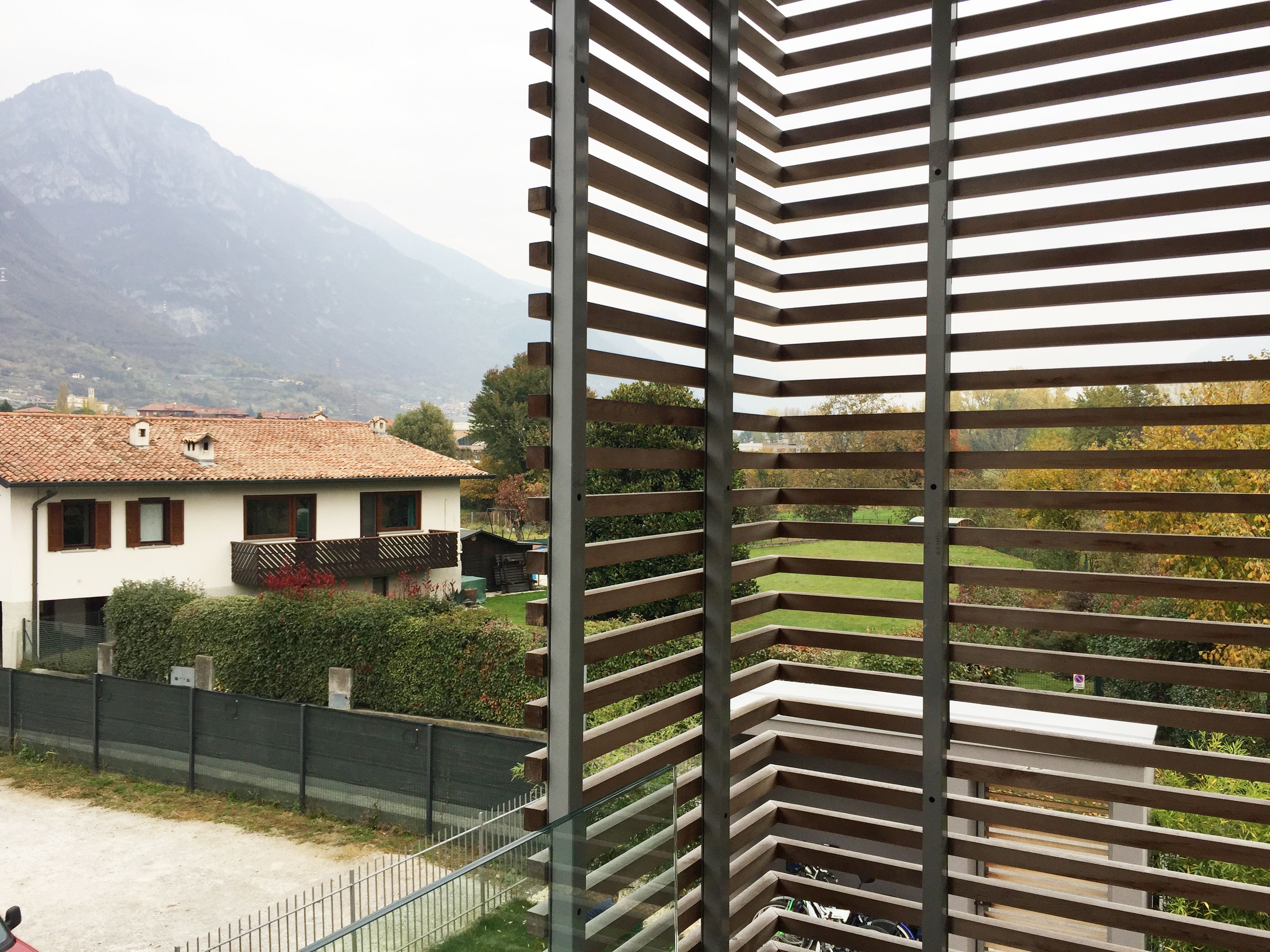 A balcony with a metal railing overlooking a residential area with houses and a mountain in the background.