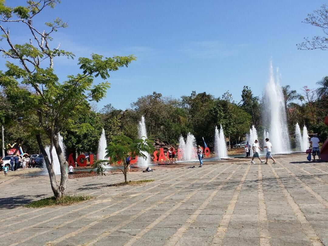 A public square with fountains, trees, and people.