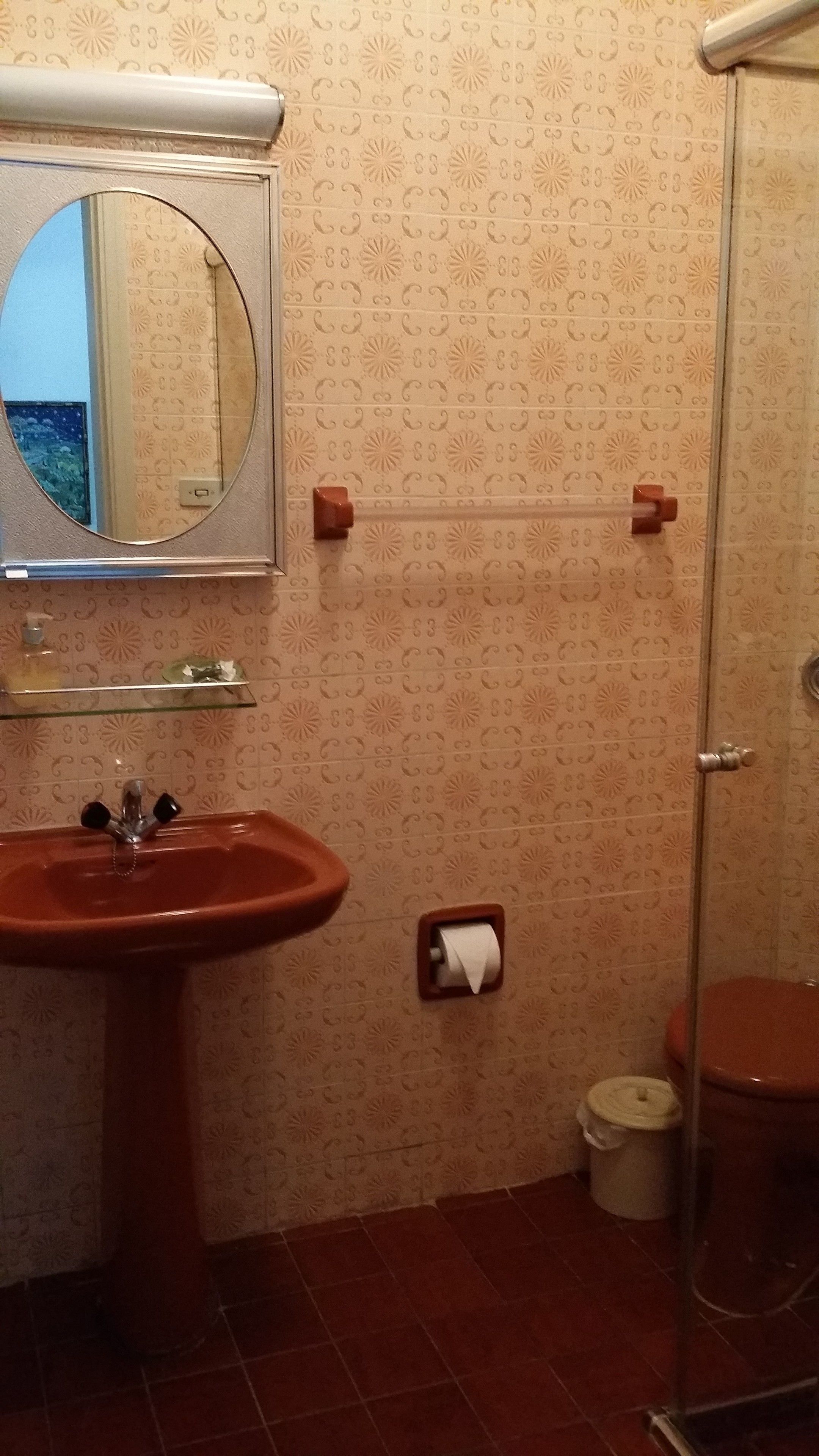 A bathroom with a sink, mirror, toilet, and shower.