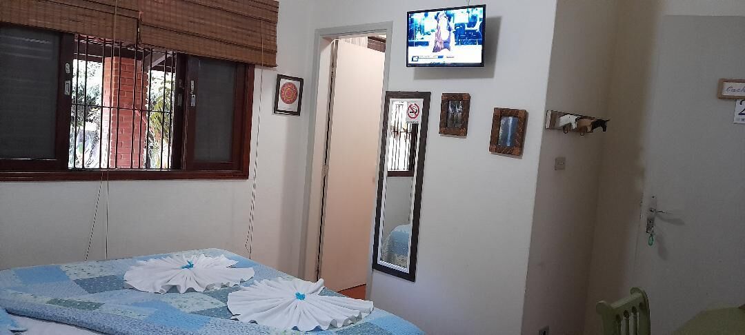 Un dormitorio con cama, televisor montado en la pared y puerta que da a otra habitación.