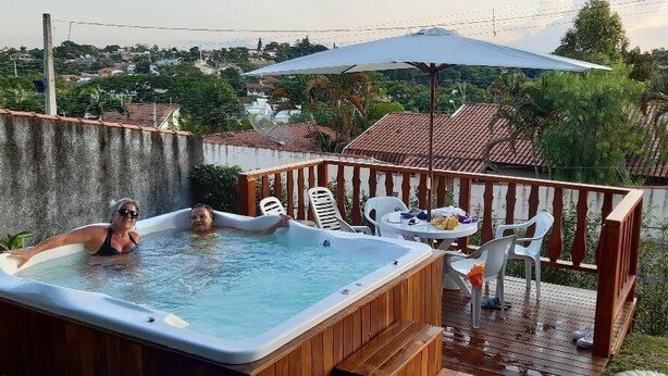 A hot tub on a wooden deck with a view of a residential area. - Suites em Águas de São Pedro (Aguas de Sao Pedro)