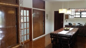 A traditional Japanese-style room with sliding doors, a wooden dining table, and a hanging light fixture. - Suites em Águas de São Pedro (Aguas de Sao Pedro)