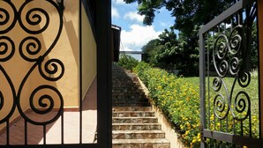 A set of stone steps leading up to a gate with intricate metalwork. - Suites em Águas de São Pedro (Aguas de Sao Pedro)