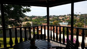 Un balcón con vistas a una zona residencial, una mesa con una planta en maceta y una silla.