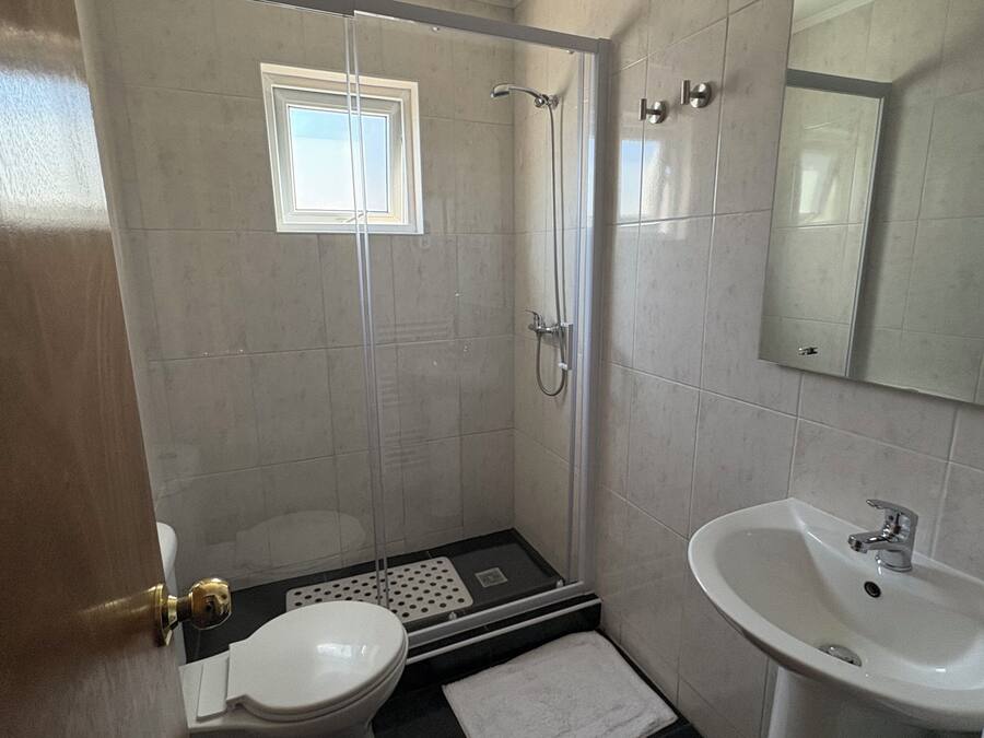 A bathroom with a toilet, shower, and sink.