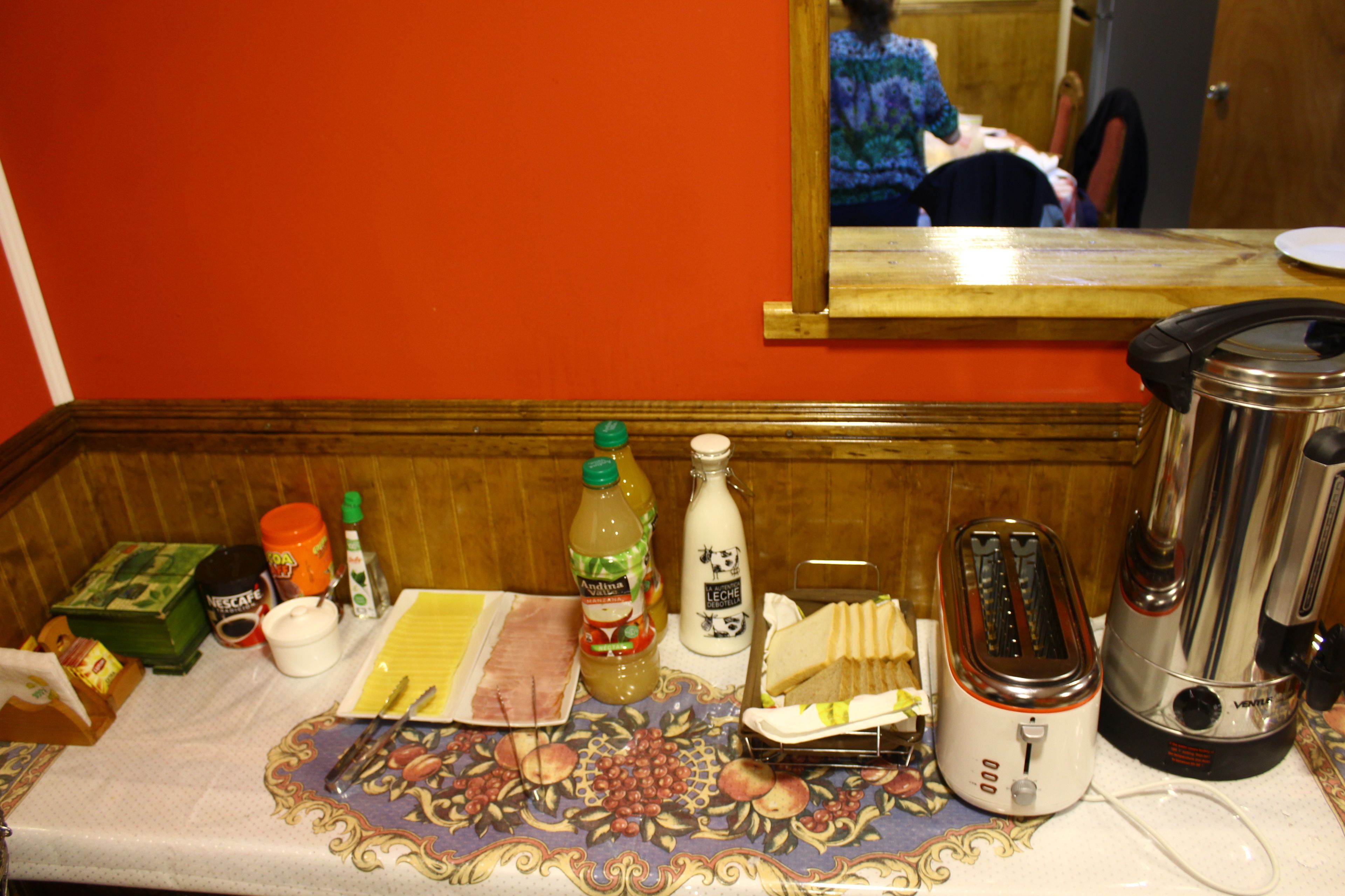 A kitchen counter with various items including a toaster, a blender, a bottle of juice, and a plate of food.