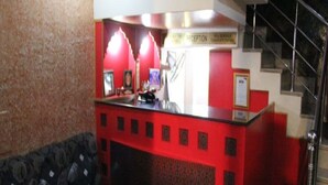 Un mostrador de recepción con una decoración en rojo y negro, un sofá y una escalera.