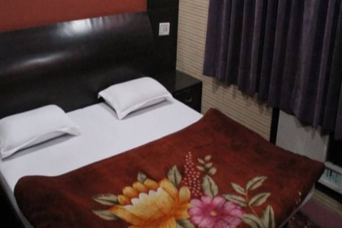 A bed with a floral bedspread, a black headboard, and a small bedside table with a lamp.