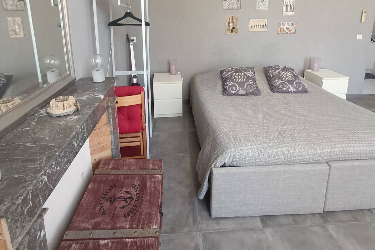 Een slaapkamer met een groot bed, een dressoir, een spiegel en een houten kist.