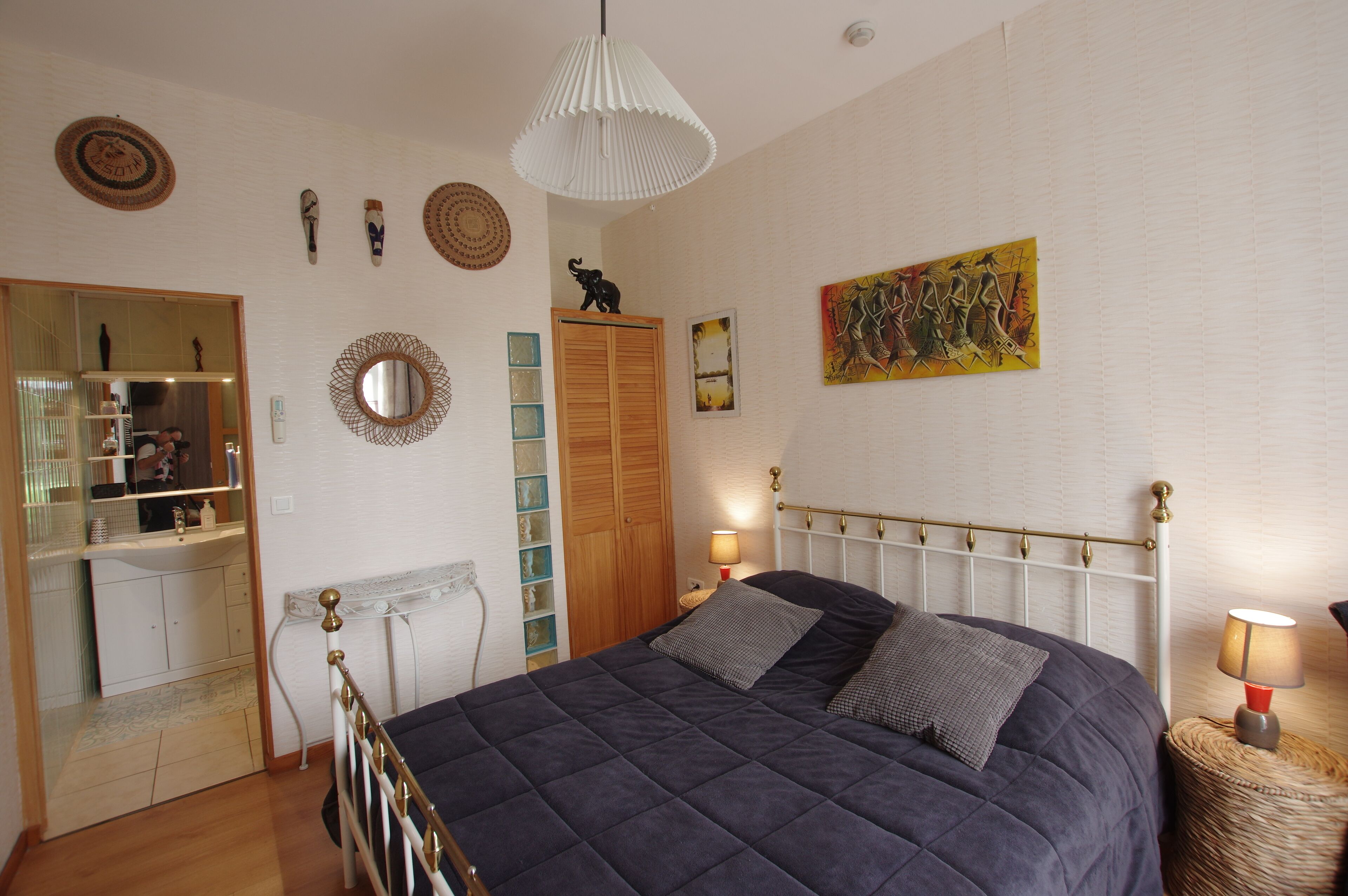 Une chambre à coucher avec un lit, des lampes de chevet, un miroir, une armoire et un tableau au mur.