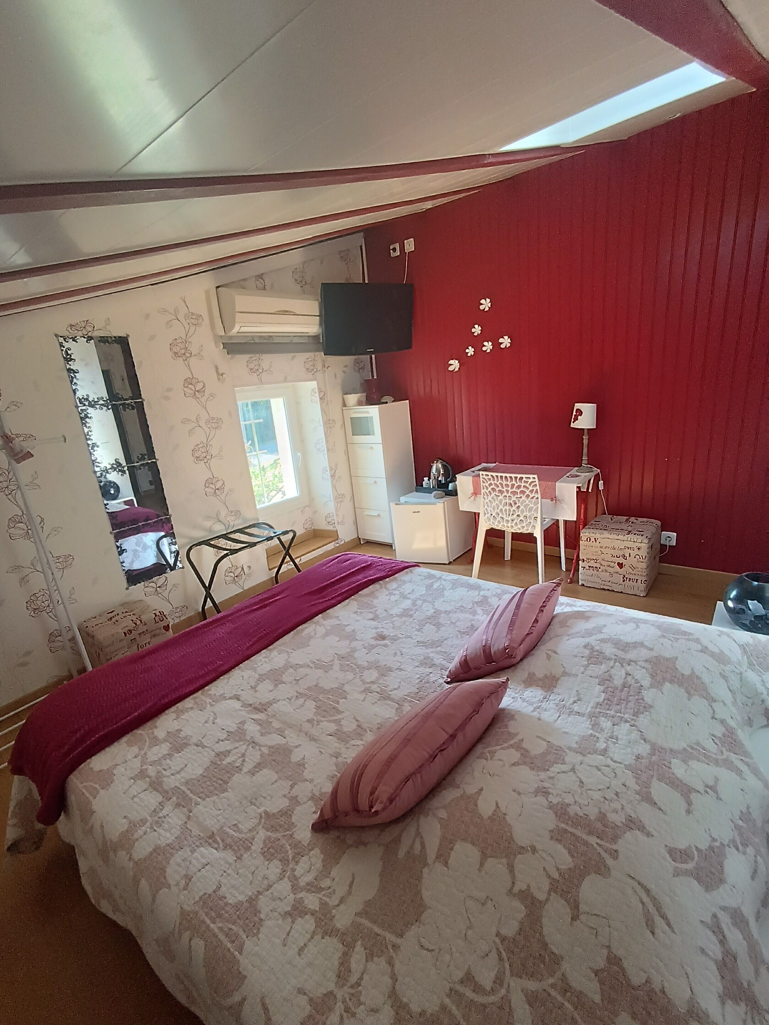 A bedroom with a bed, a desk, a chair, and a TV.