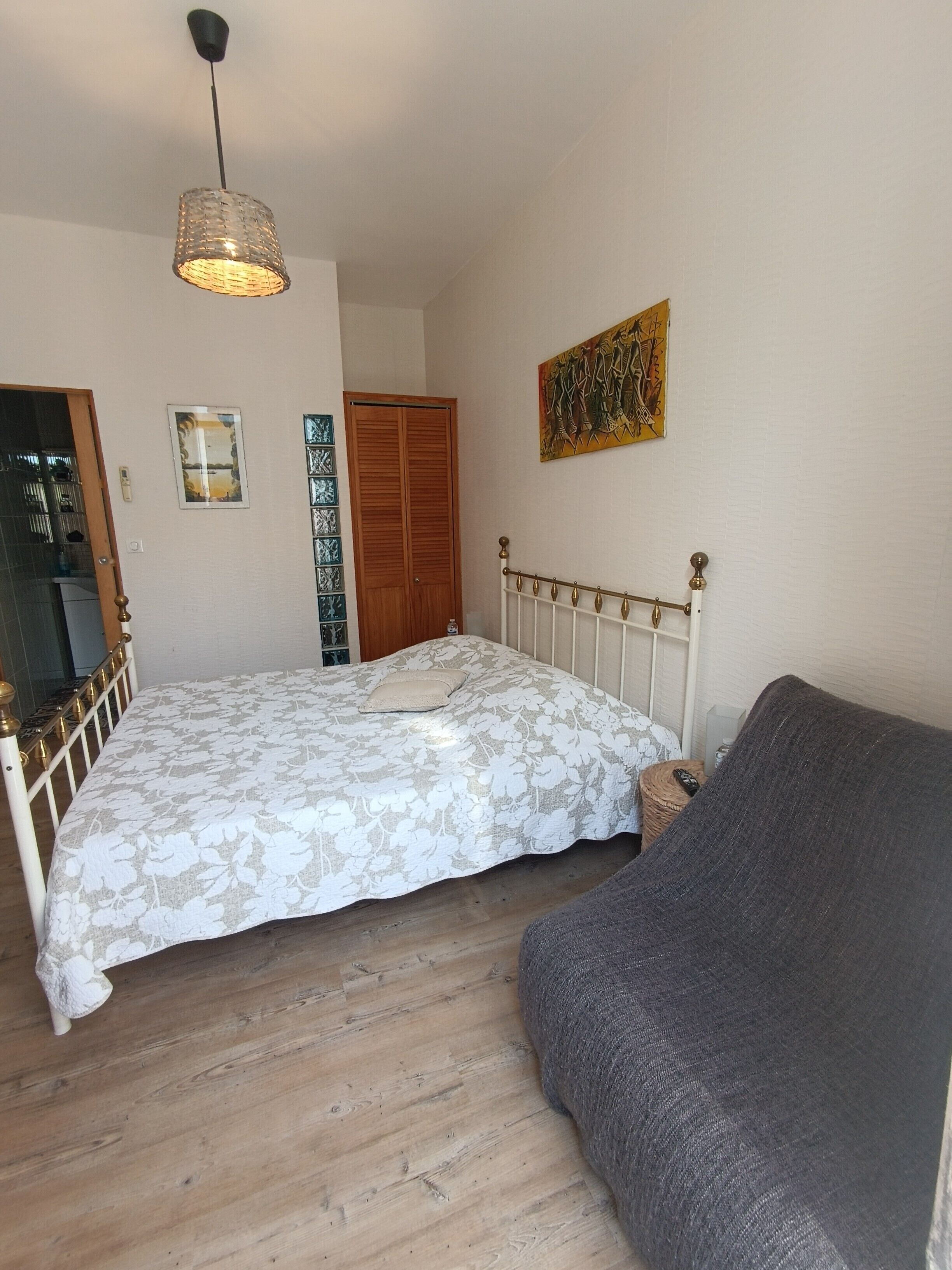 A bedroom with a bed, a bedside table, a lamp, a wardrobe, and a painting on the wall.
