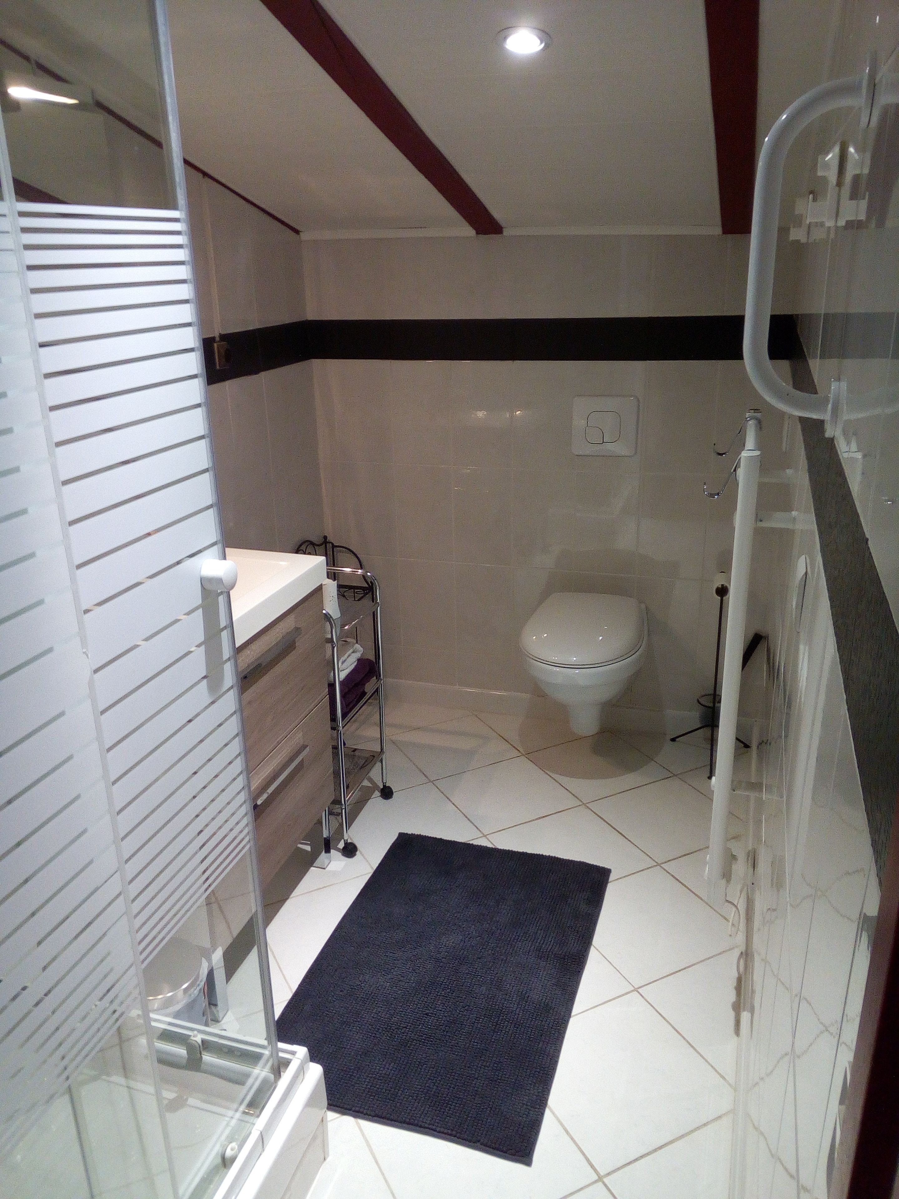 A compact bathroom with a toilet, sink, and shower area.