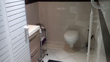 A compact bathroom with a toilet, sink, and shower area.