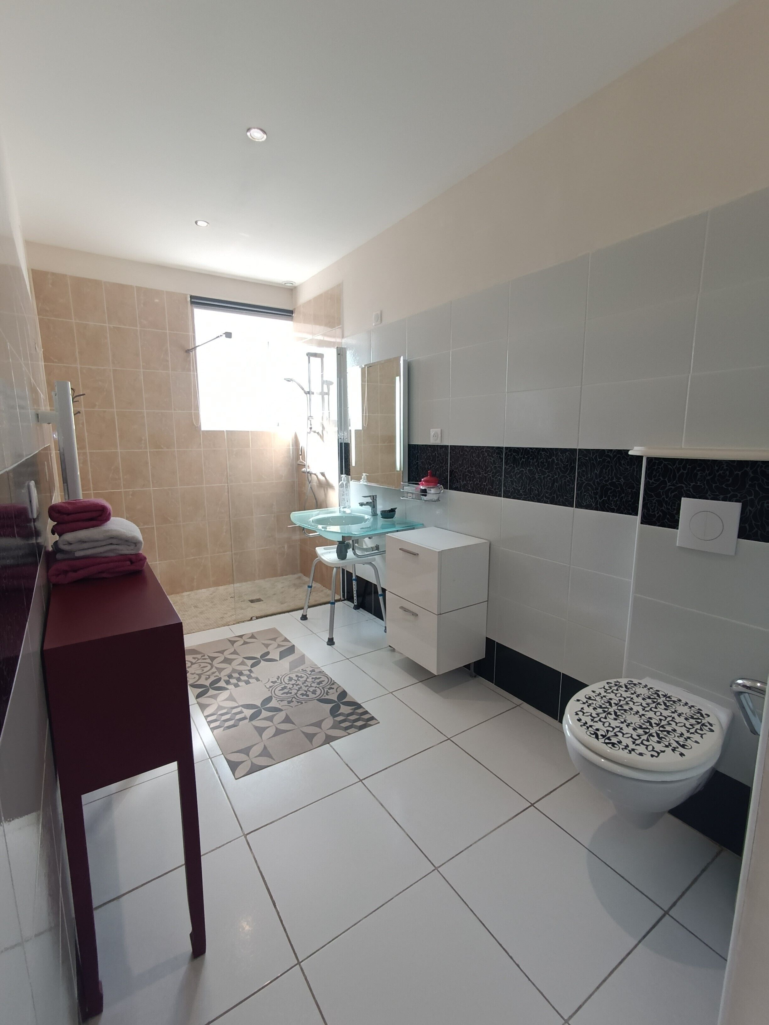 Un baño moderno con cabina de ducha de vidrio, un lavabo blanco y un inodoro con cubierta decorativa.