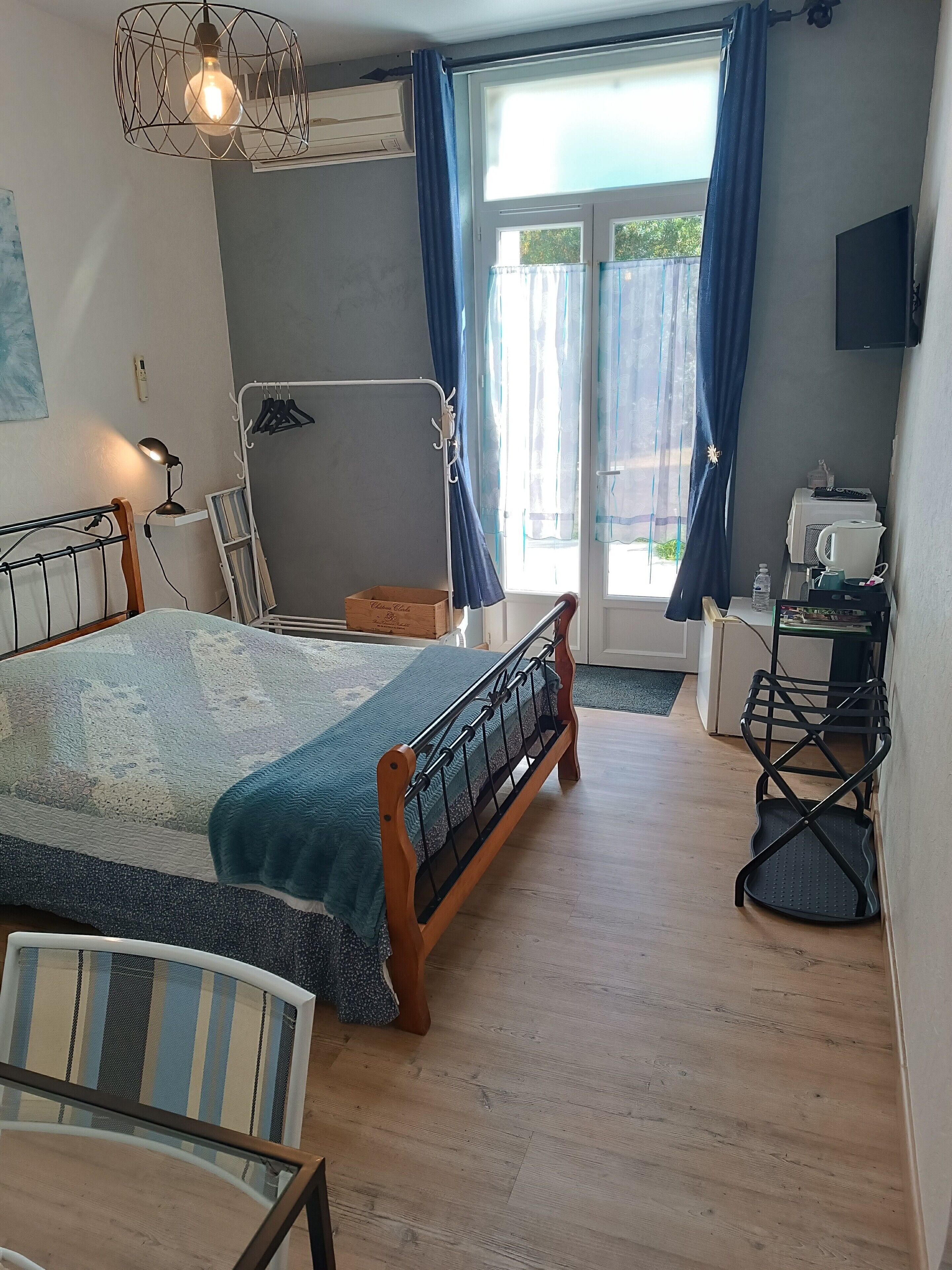 Un dormitorio con cama, escritorio, silla, lámpara colgante y ventana con cortinas.
