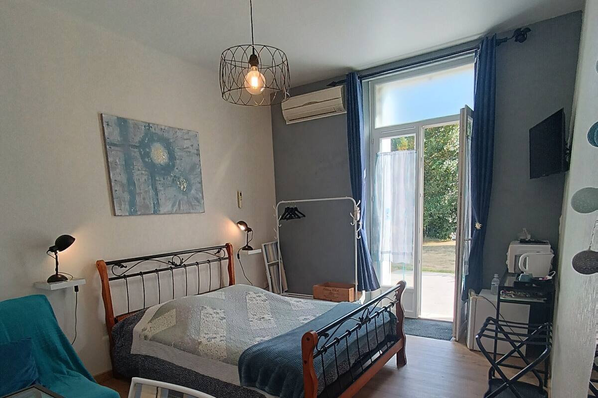 Een slaapkamer met een bed, een stoel, een bureau en een raam met gordijnen.