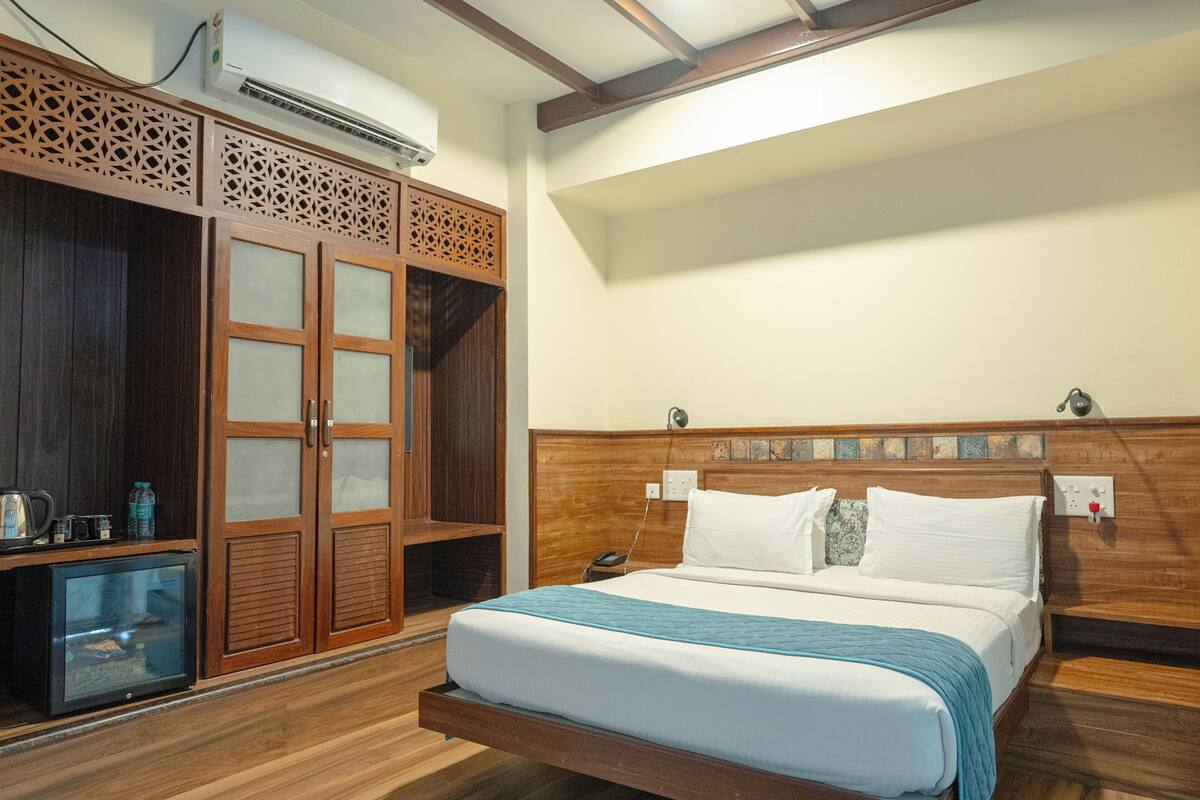A room with a bed, wooden wardrobe, and a small TV.