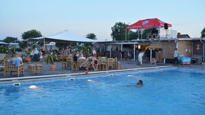 Un espace piscine avec des chaises longues et un coin salon abrité.