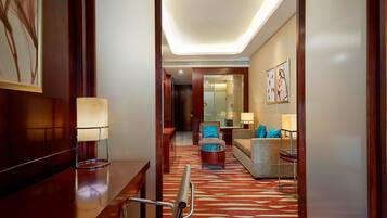 A hotel lobby with a wooden reception desk, a glass coffee table, a sofa, and a patterned carpet.