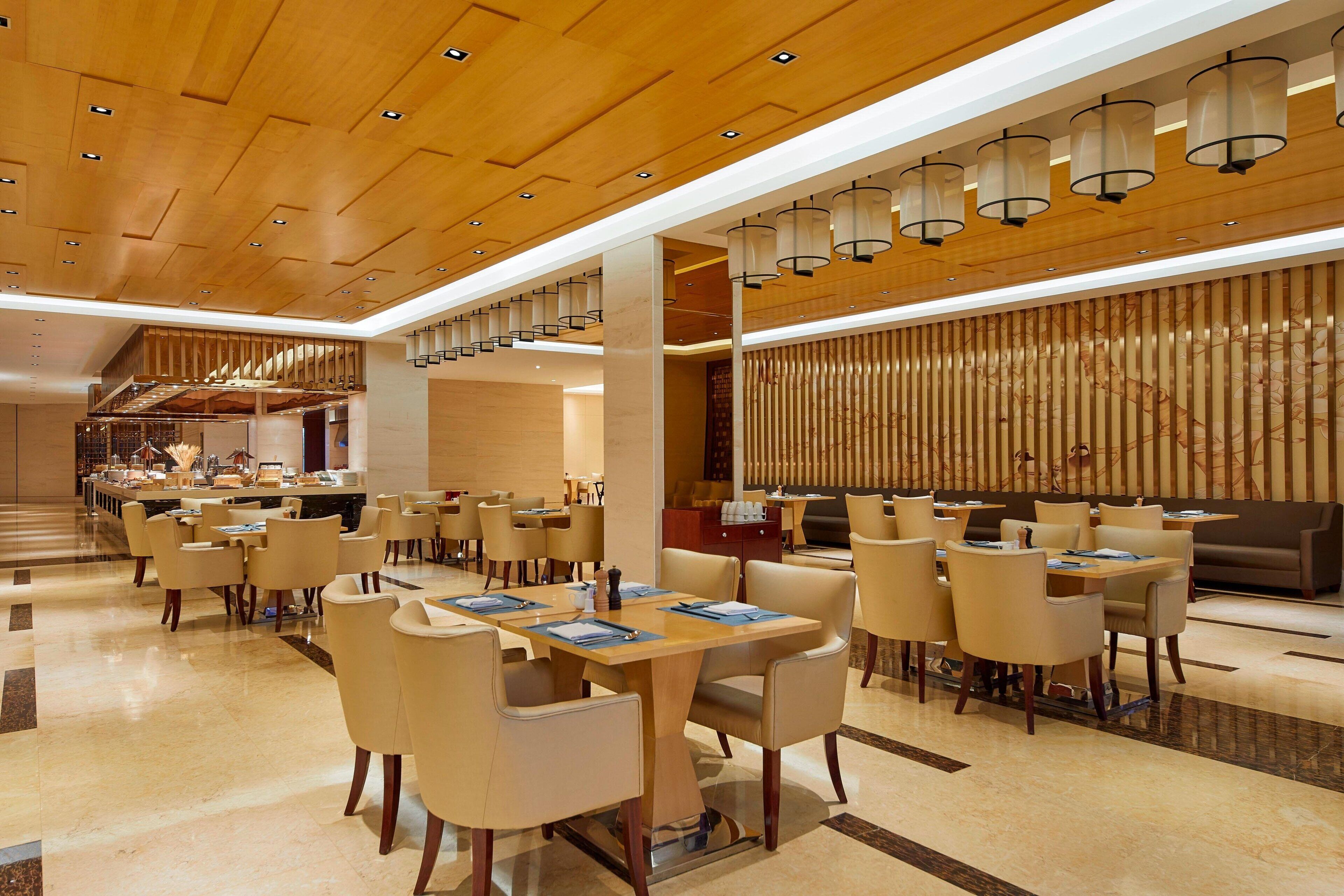A spacious hotel lobby with multiple seating areas, a staircase, and a reception desk.